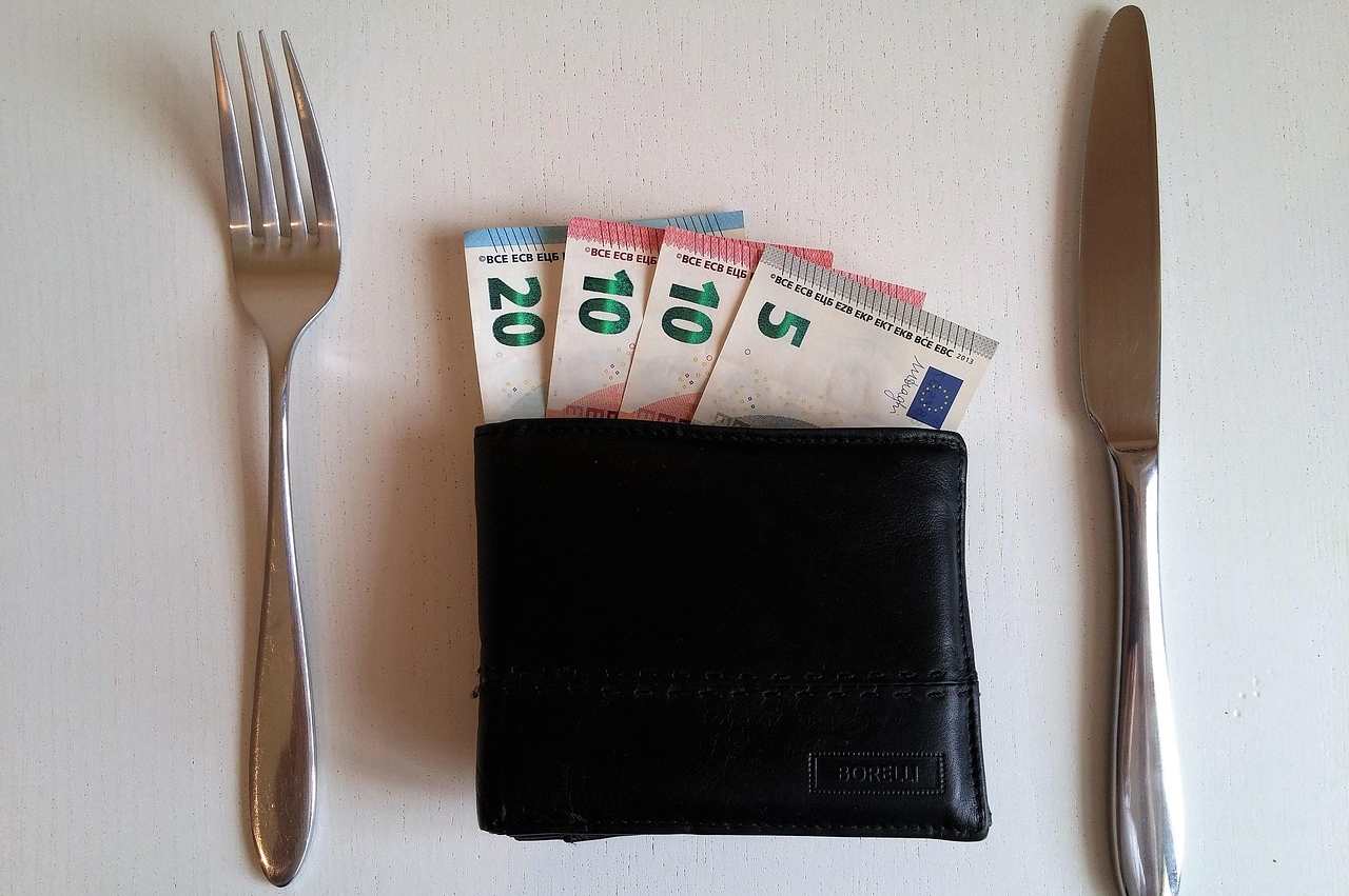Portafoglio con banconote euro e forchetta e coltello