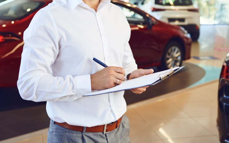 Uomo in concessionario che firma una pratica auto prima di darla al cliente