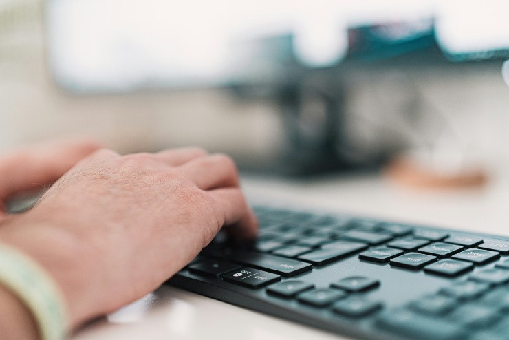 mani di una persona sulla tastiera del pc