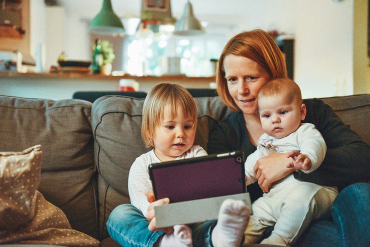Nanna con due bambini piccoli che guardano il tablet sul divano