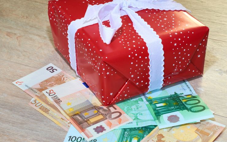 Banconote euro sotto a un pacco regalo