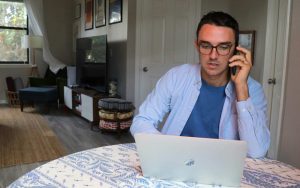 Uomo davanti al pc che riceve una telefonata dal datore di lavoro