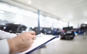 Concessionario sullo sfondo e dipendente che compila un foglio in primo piano