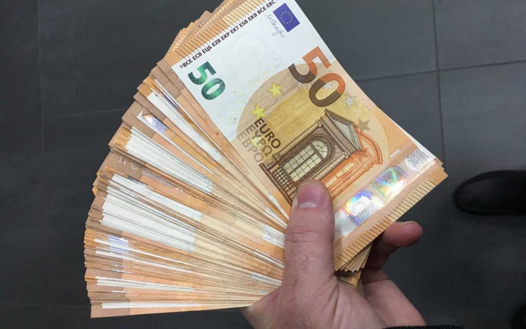 uomo che tiene in mano un ventaglio di banconote da 50€: quindicesima mensilità