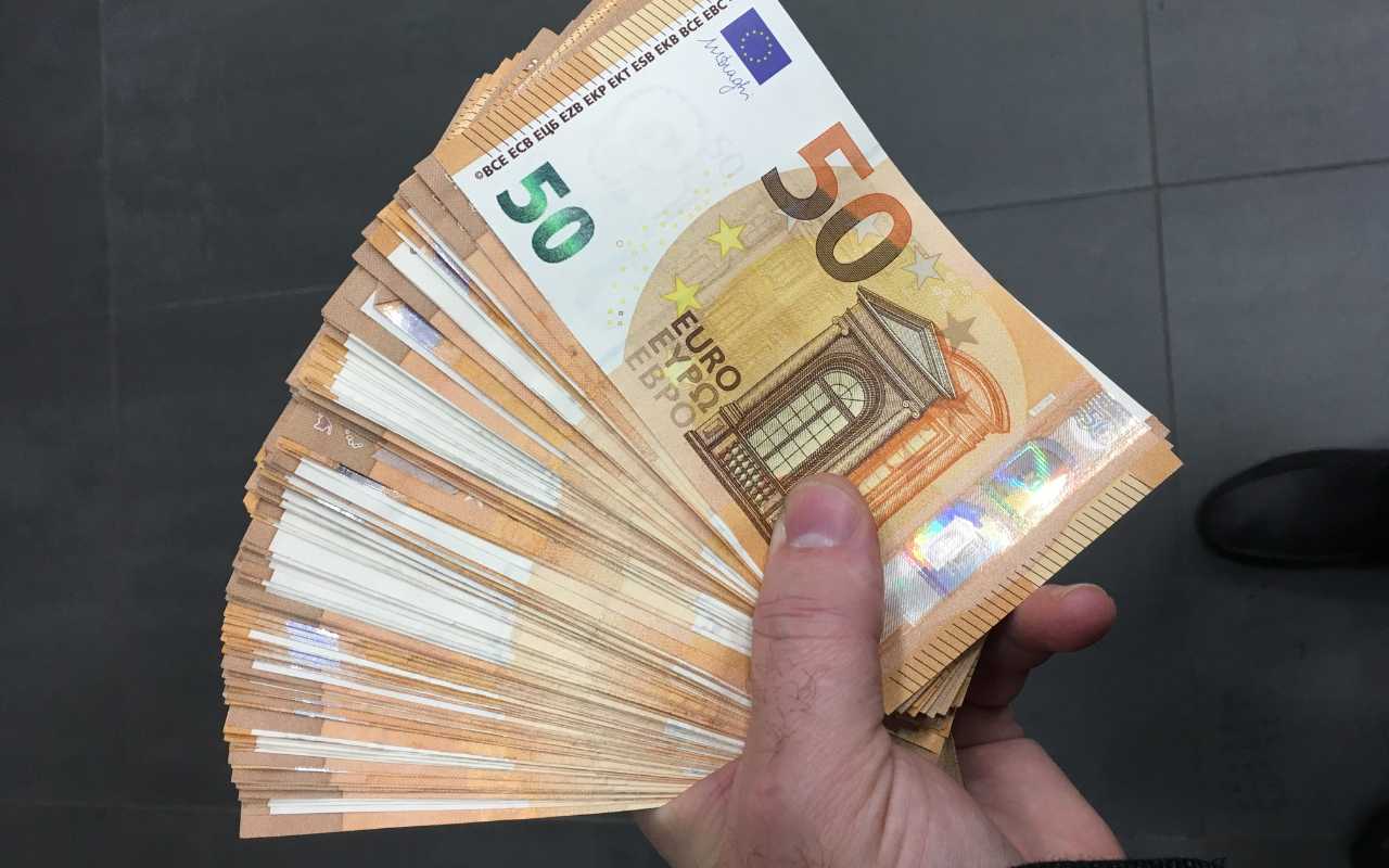 uomo che tiene in mano un ventaglio di banconote da 50€: quindicesima mensilità